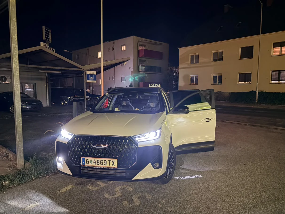 Weißes Taxi mit geöffneter Tür in Graz bei Nacht